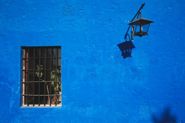 Bright blue wall with window and lantern shadow in Arequipa, Peru.